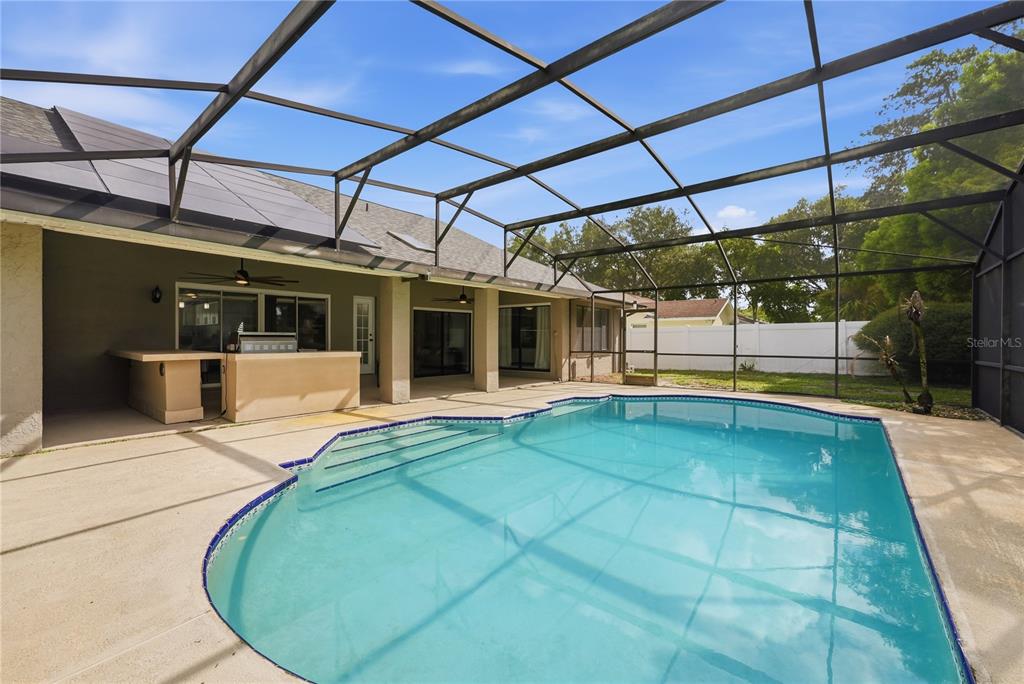 A screened-in patio features a swimming pool, a built-in outdoor kitchen, and a concrete deck — 1539 ELF STONE DRIVE, CASSELBERRY, FL