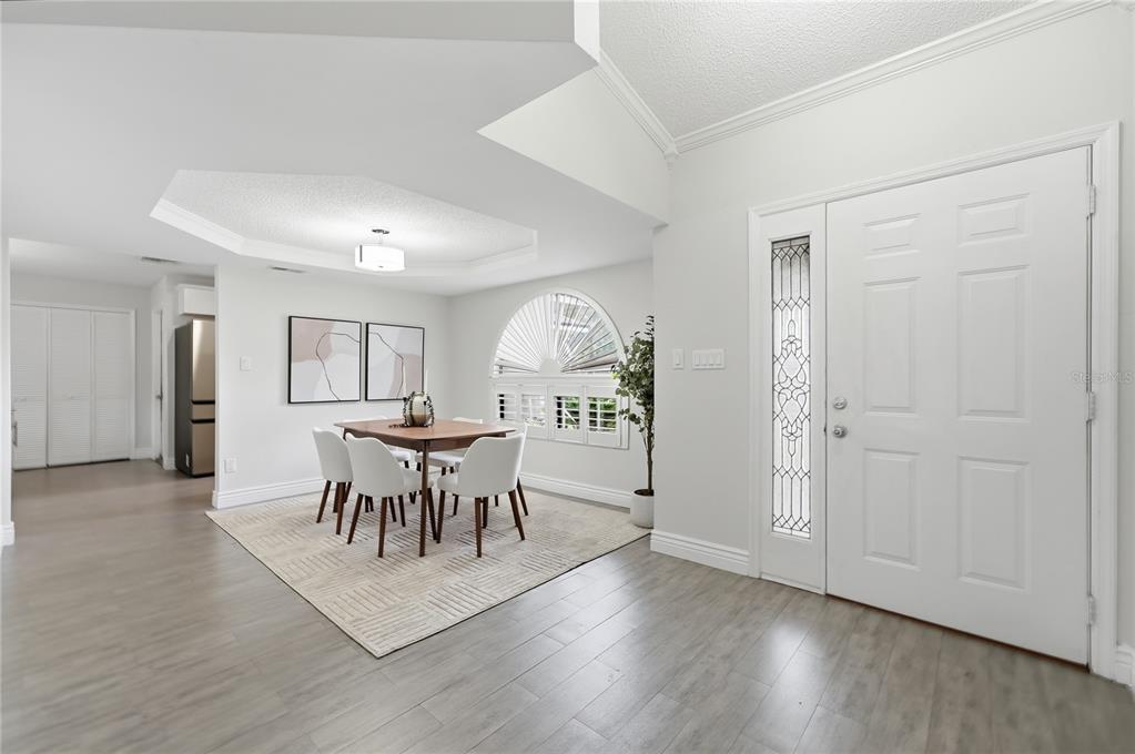 A dining area with a tray ceiling, wood table, white chairs, and a front door — 1539 ELF STONE DRIVE, CASSELBERRY, FL