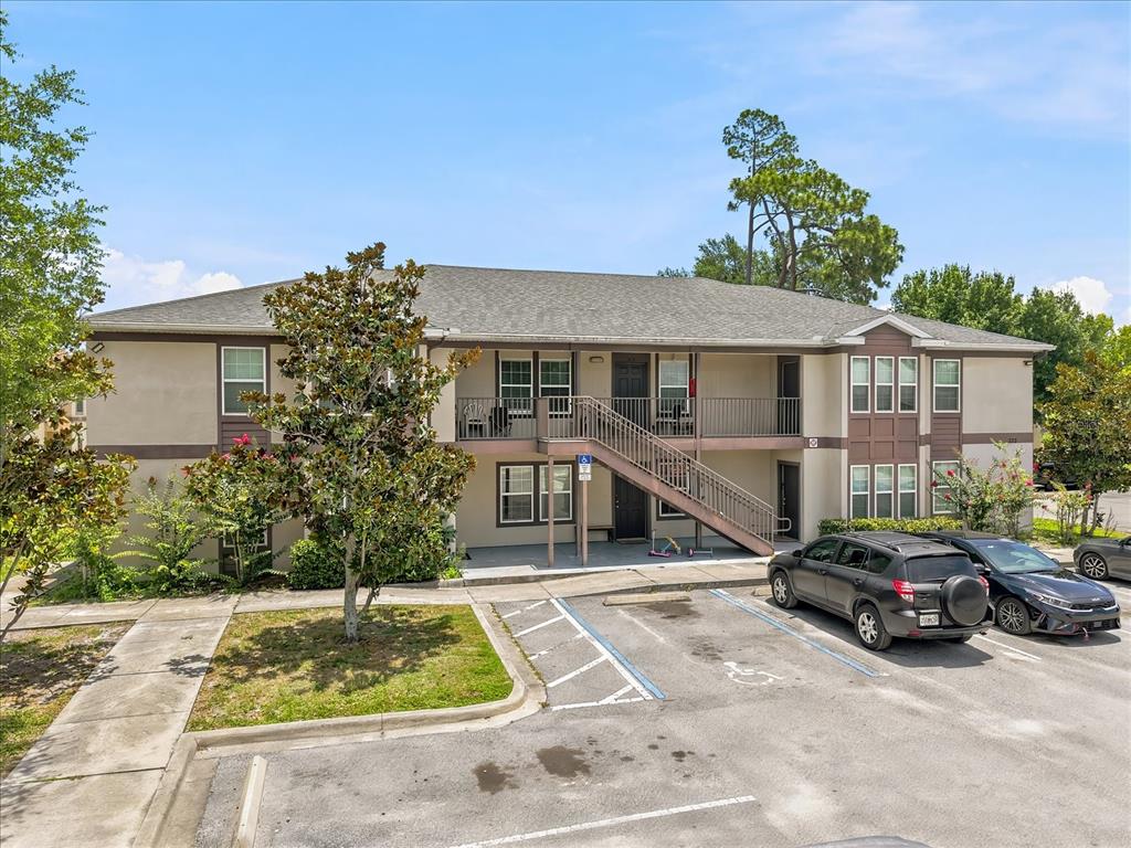 A two-story apartment building with a staircase, balcony, and a parking lot in front — 272 HART LANE, KISSIMMEE, FL