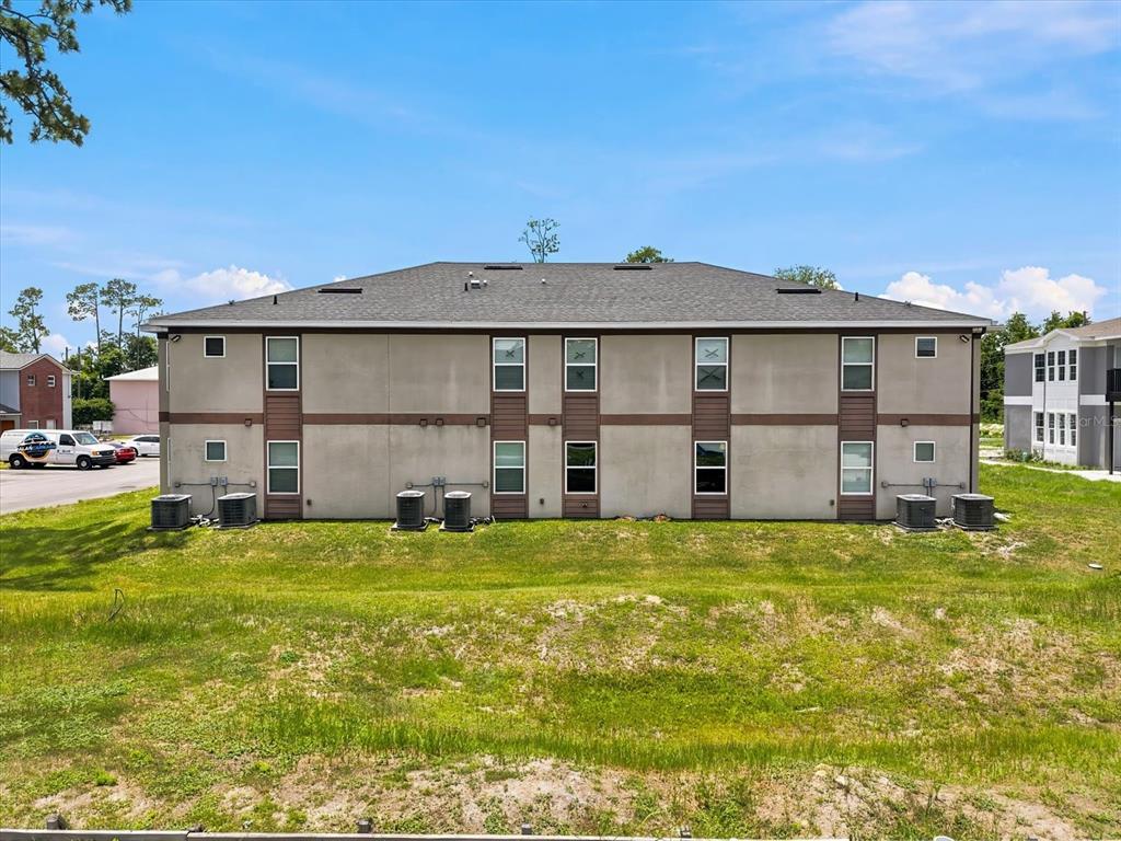 A two-story apartment building exterior with a gray stucco facade and multiple air conditioning units — 272 HART LANE, KISSIMMEE, FL