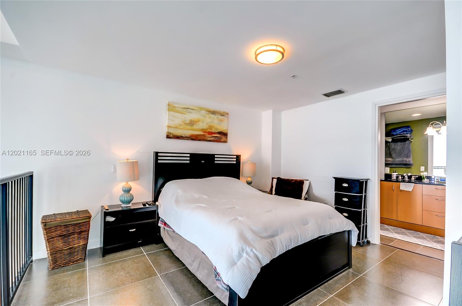 A bedroom features a black bed frame, tile flooring, and an attached bathroom — 300 S Biscayne Bluv # 1022, Miami FL 33131, MIAMI, FL