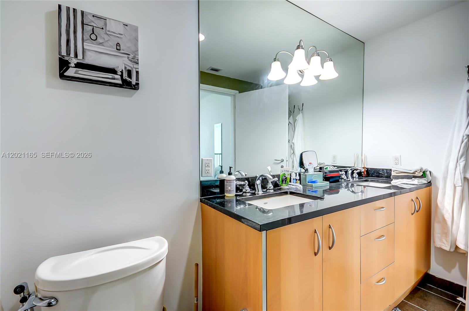 A bathroom features a light wood vanity with a black countertop and a large mirror — 300 S Biscayne Bluv # 1022, Miami FL 33131, MIAMI, FL