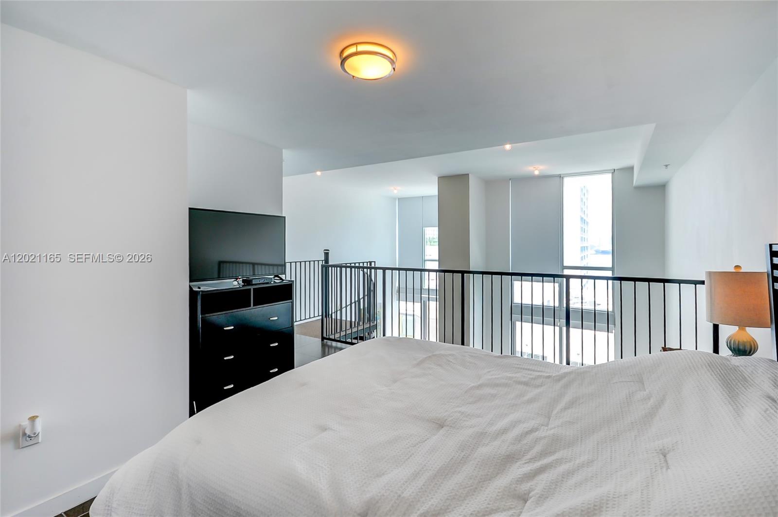 A bedroom loft overlooks a lower level through a black metal railing — 300 S Biscayne Bluv # 1022, Miami FL 33131, MIAMI, FL