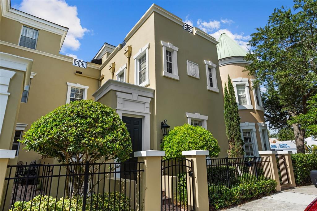 A tan multi-story building with a turret and black metal fencing stands outdoors — 2419 VICTORIA GARDENS LANE, TAMPA, FL
