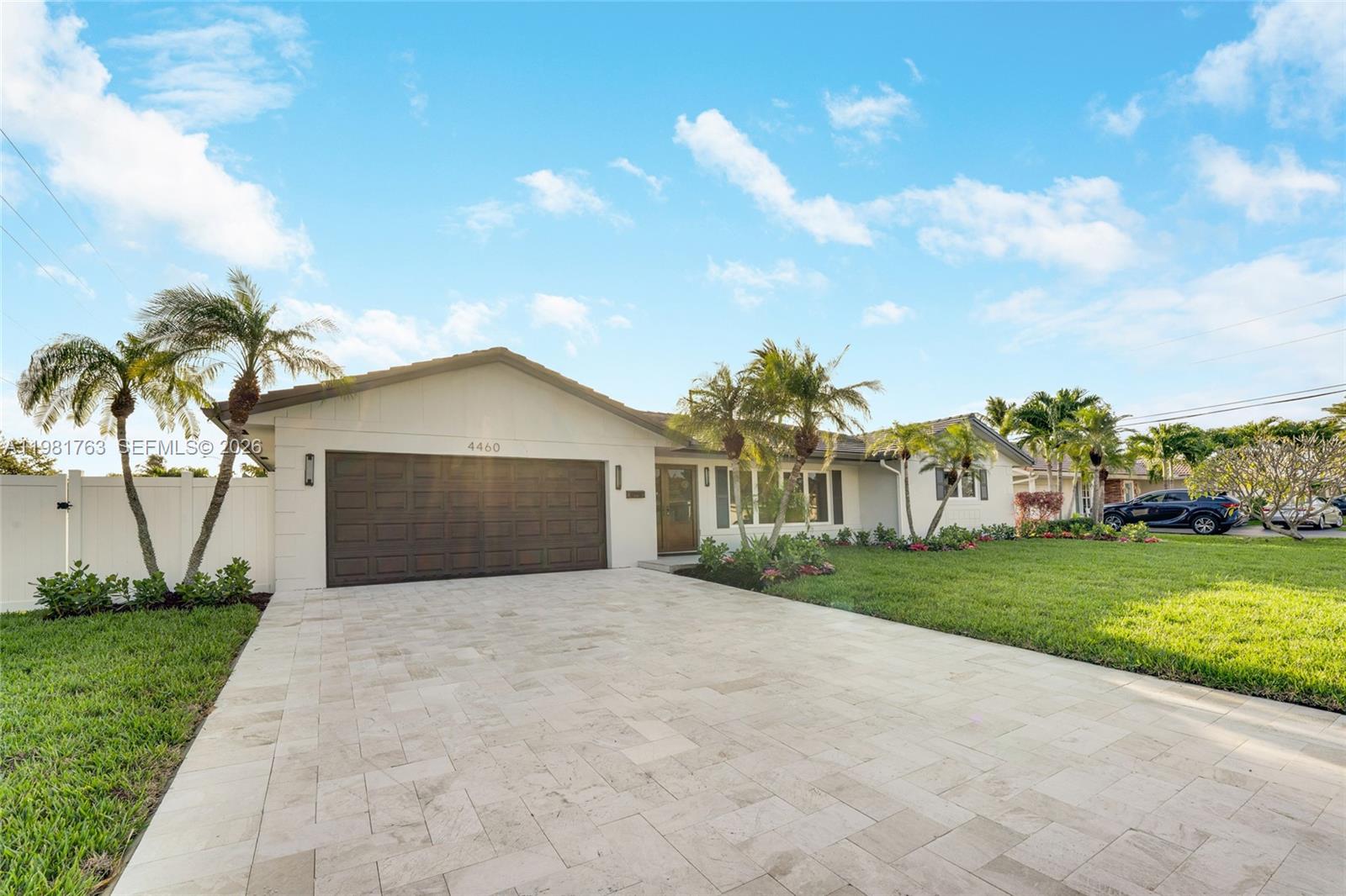 A single-story house with a paved driveway, a dark garage door, and palm trees — 4460 NE 25th Ave, Lighthouse Point FL 33064, LIGHTHOUSE POINT, FL