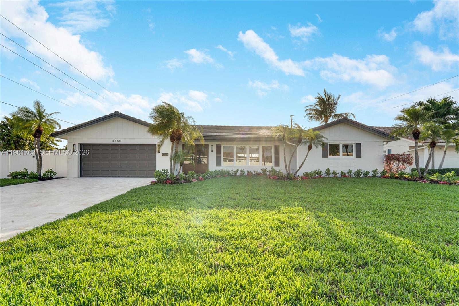 A single-story house with a white exterior, a two-car garage, and a manicured front lawn — 4460 NE 25th Ave, Lighthouse Point FL 33064, LIGHTHOUSE POINT, FL