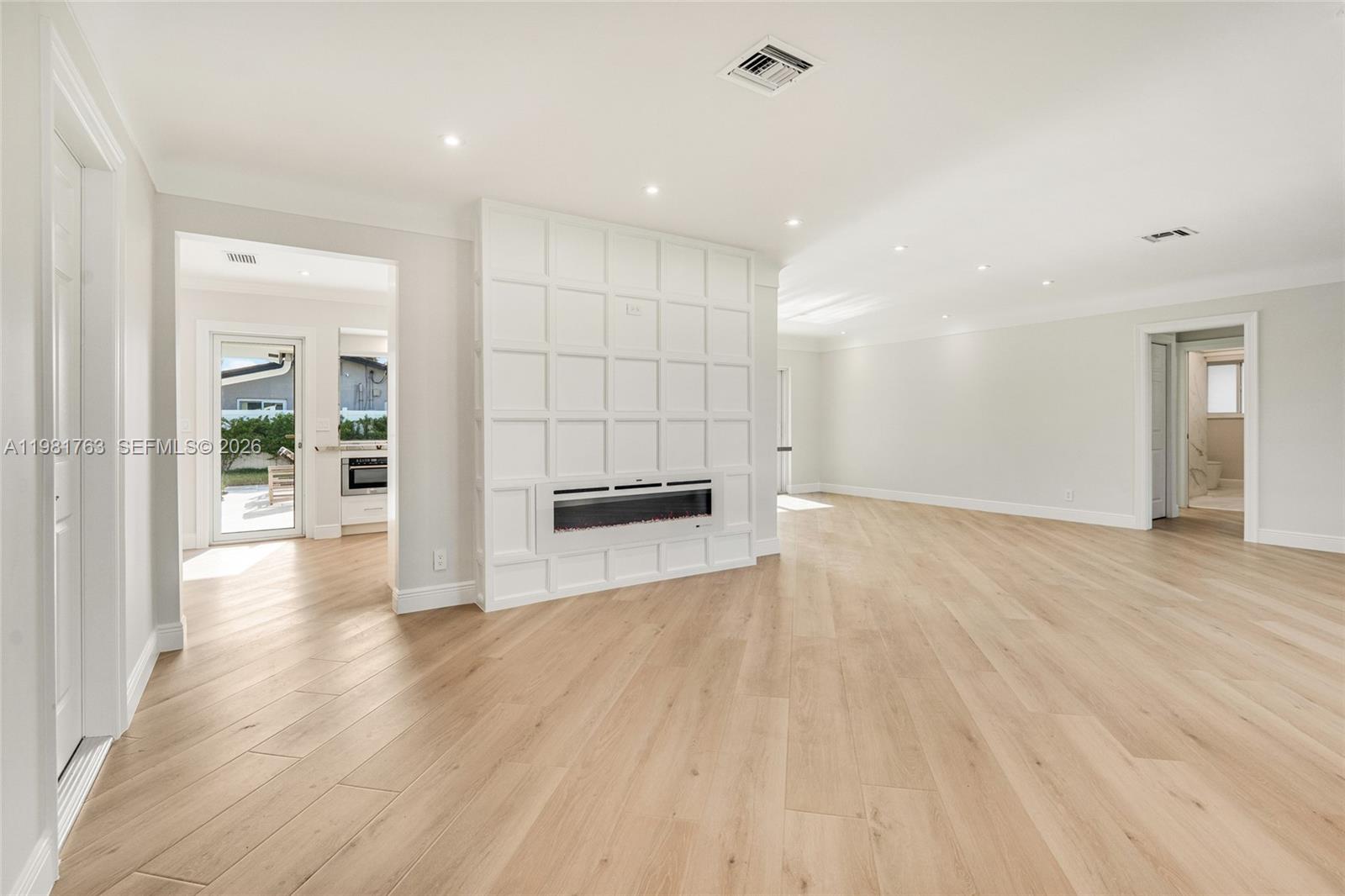 A bright living room features light wood flooring, a white paneled fireplace, and recessed lighting — 4460 NE 25th Ave, Lighthouse Point FL 33064, LIGHTHOUSE POINT, FL