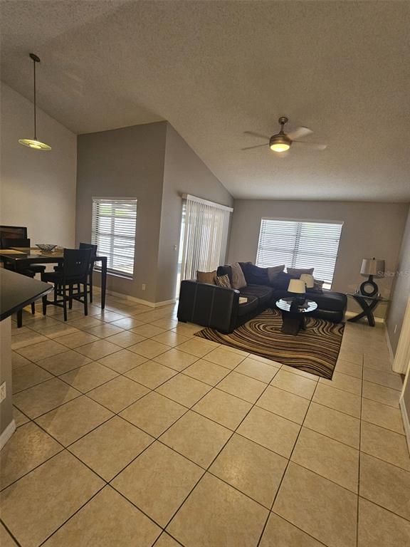 A living and dining area features tile floors, vaulted ceilings, and a ceiling fan — 12718 TROWBRIDGE LANE, TAMPA, FL