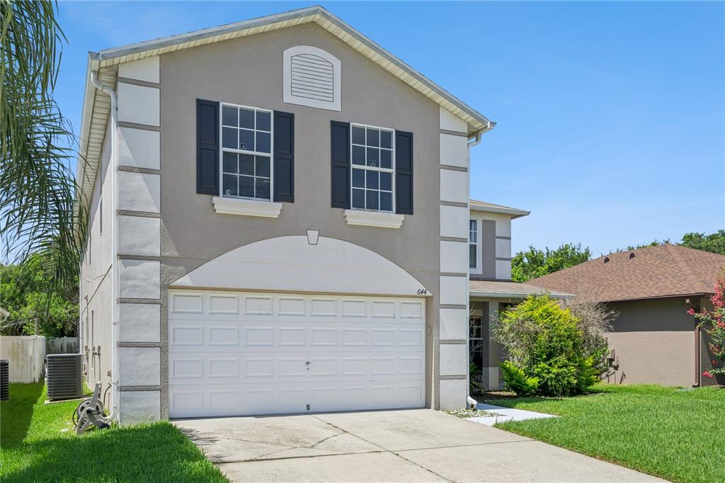 A two-story house with a beige stucco exterior, white trim, and a two-car garage — 644 FLOWER FIELDS LANE, ORLANDO, FL