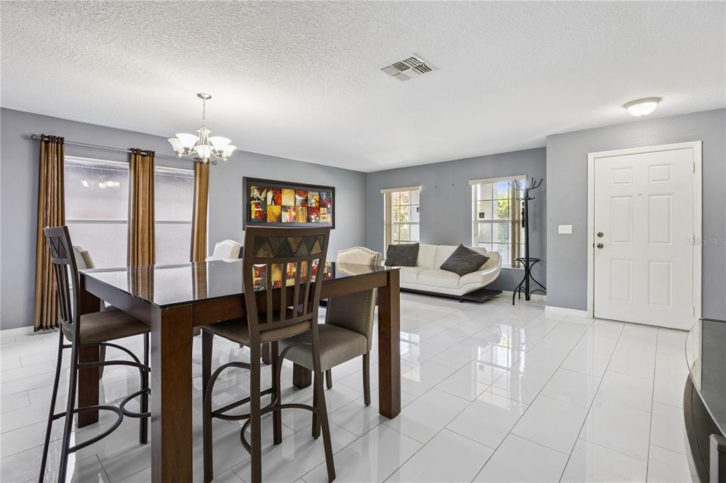 A dining area with a dark wood table and chairs sits on white tile flooring — 644 FLOWER FIELDS LANE, ORLANDO, FL