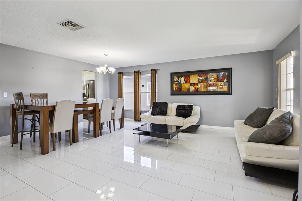 A dining and living area with white tile floors, grey walls, and two white sofas — 644 FLOWER FIELDS LANE, ORLANDO, FL