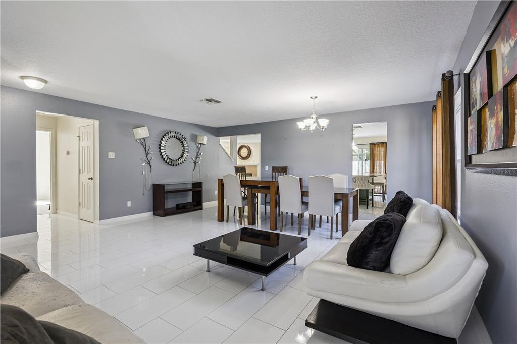 A living and dining room with white tile floors, gray walls, and modern furniture — 644 FLOWER FIELDS LANE, ORLANDO, FL