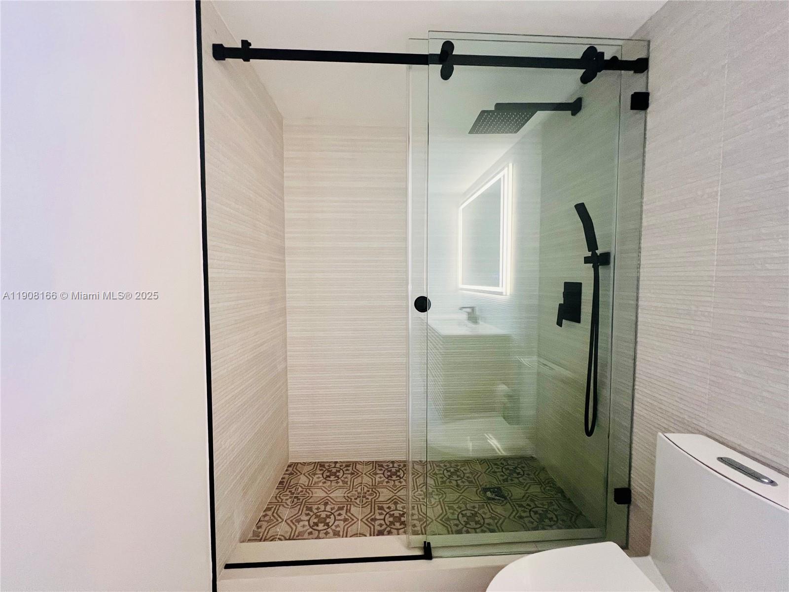 A modern bathroom features a walk-in shower with patterned tile flooring and glass doors — 201 Jefferson Ave # 4C, Miami Beach FL 33139, MIAMI BEACH, FL