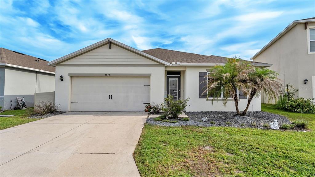 A single-story house with a two-car garage, a palm tree, and a concrete driveway — 5853 ARLINGTON RIVER DRIVE, LAKELAND, FL