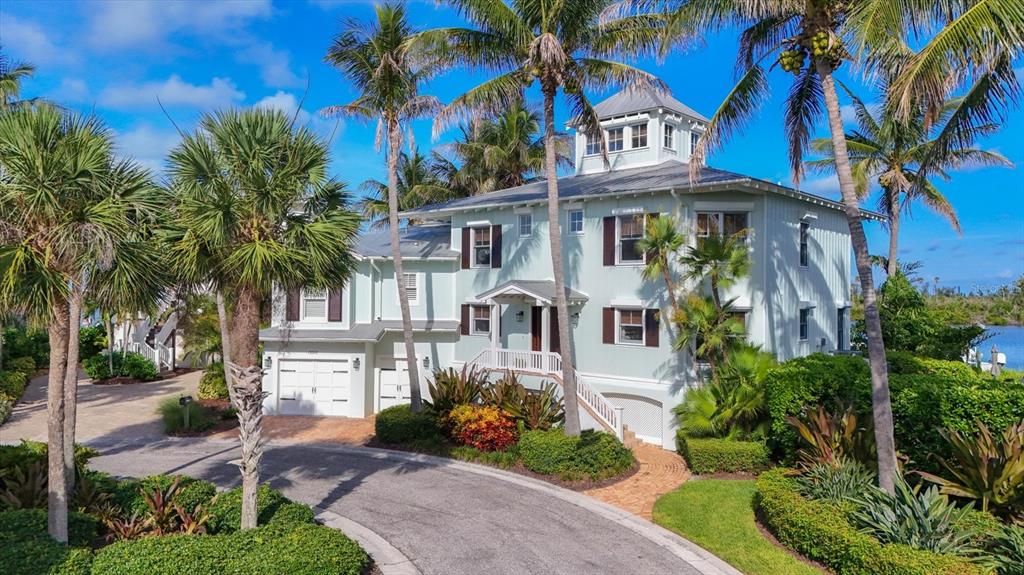 A light blue three-story coastal home with a metal roof surrounded by palm trees — 13310 ANGLERS WAY, PLACIDA, FL