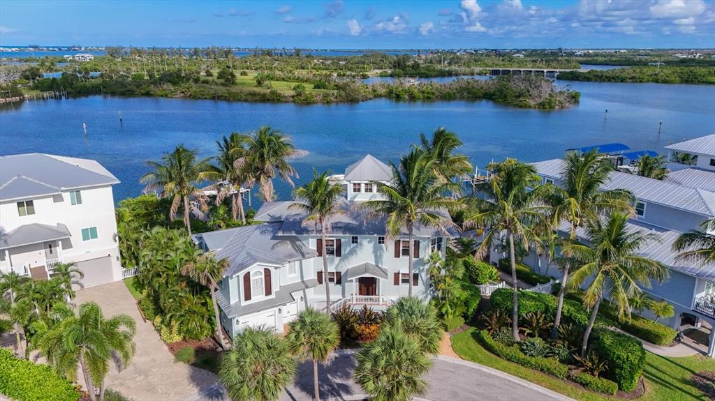 An aerial view shows a multi-story coastal house with a metal roof and palm trees — 13310 ANGLERS WAY, PLACIDA, FL