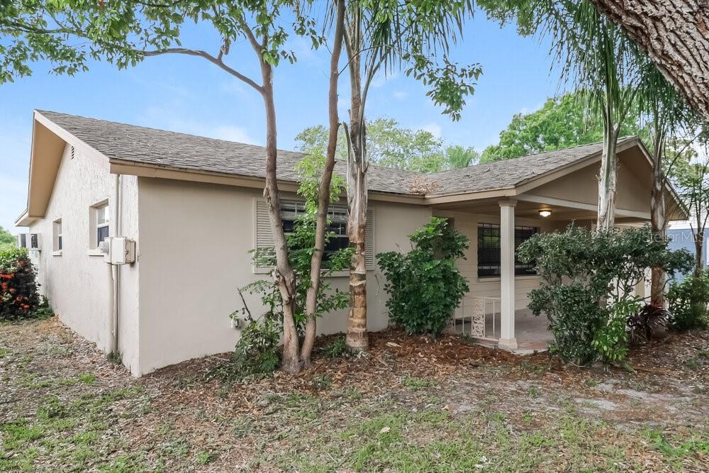 A single-story house with a beige exterior, a covered front porch, and surrounding trees — 4347 OTTER WAY, NEW PORT RICHEY, FL
