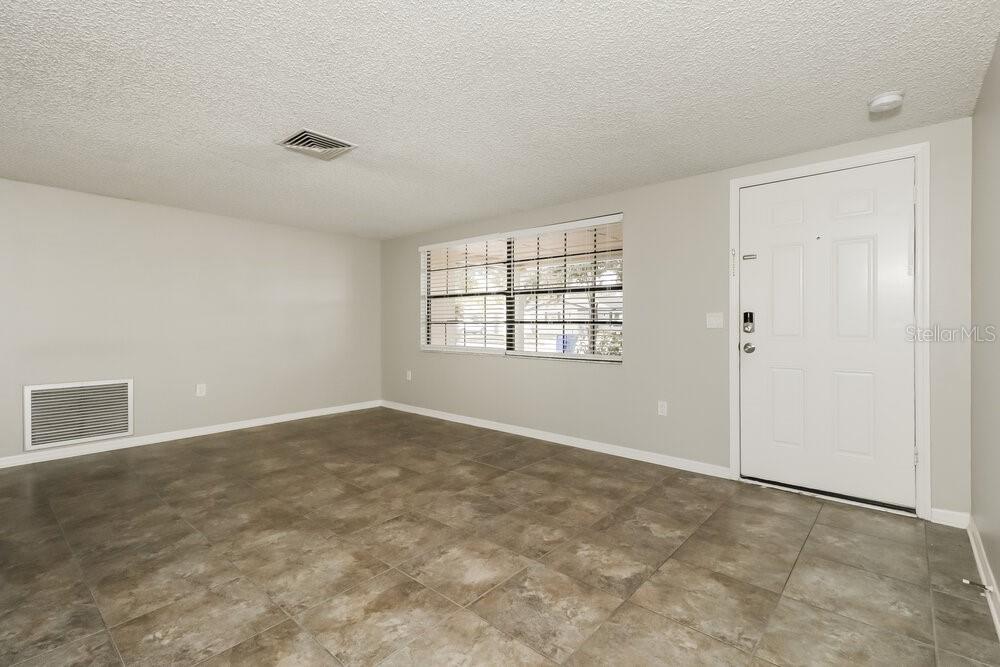 An empty room with light gray walls, tile flooring, a window, and a white door — 4347 OTTER WAY, NEW PORT RICHEY, FL