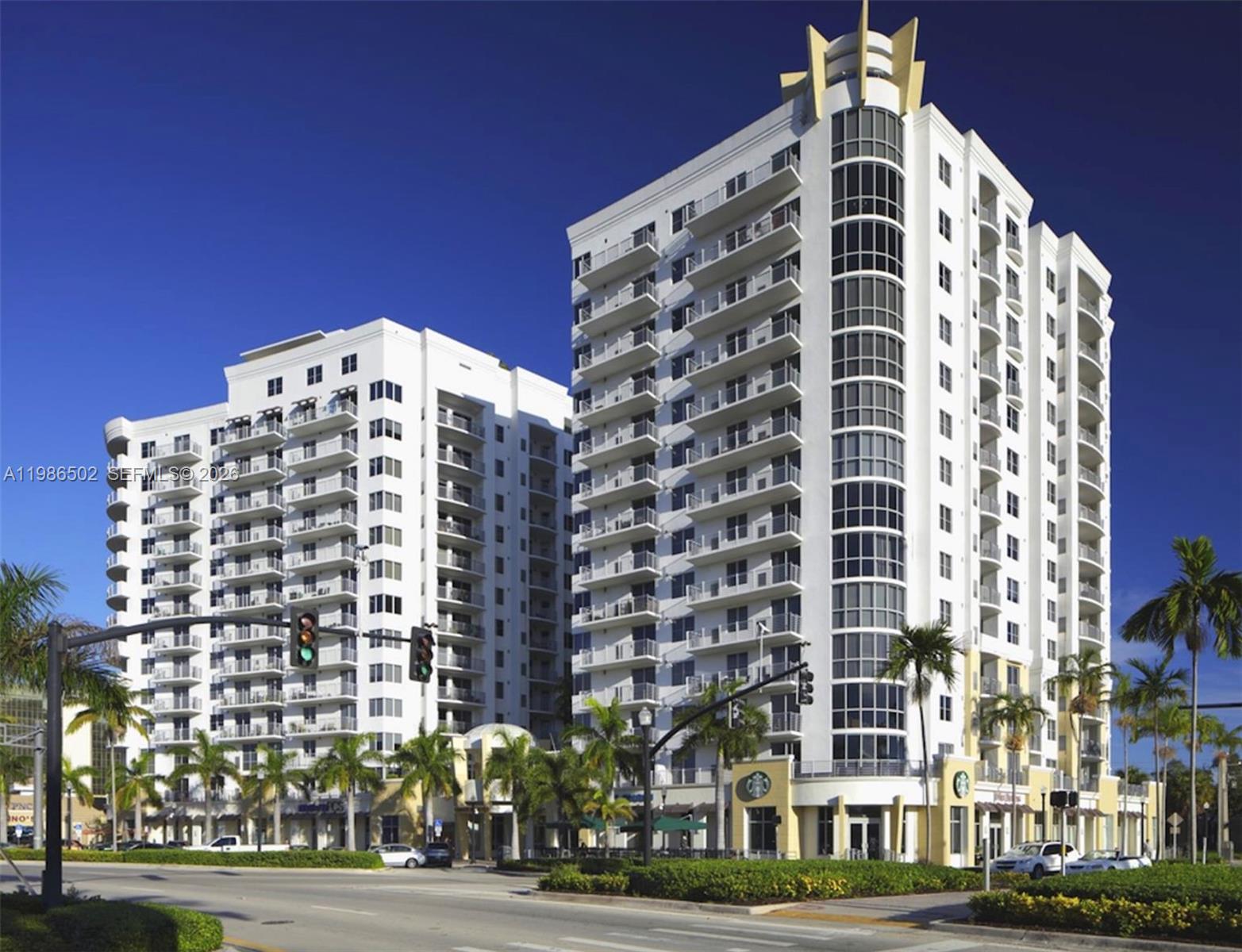 A low-angle exterior view of two white high-rise apartment buildings with balconies and ground-floor retail — 1830 Radius Dr # 522, Hollywood FL 33020, HOLLYWOOD, FL