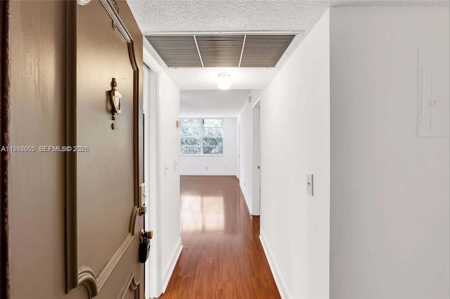 A view from an open doorway looks down a hallway with wood-look flooring toward a window — 9430 Live Oak Pl # 407, Davie FL 33324, DAVIE, FL