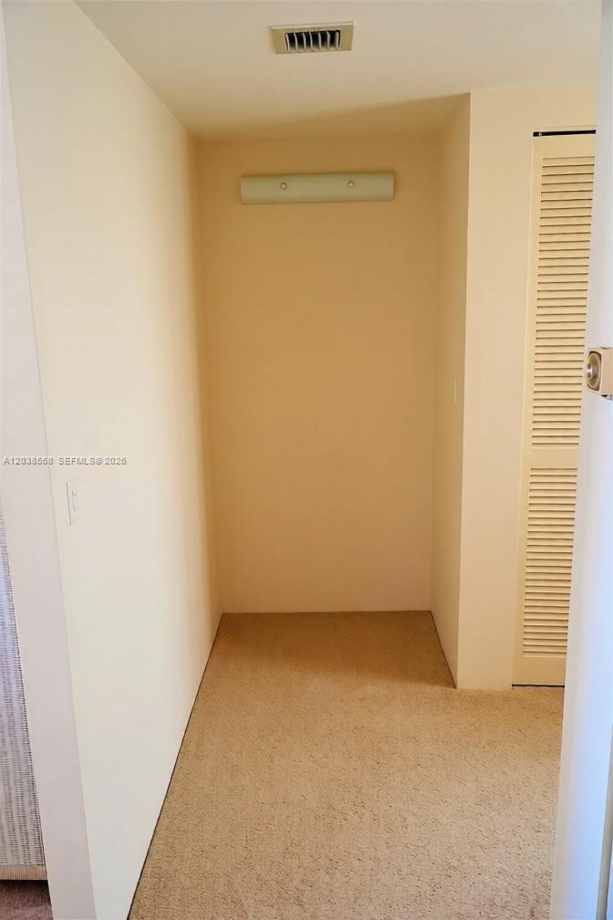 This is a small, carpeted walk-in closet with a light fixture and louvered door — 2828 Atlantic Ave # 0, Daytona FL 32118, DAYTONA, FL