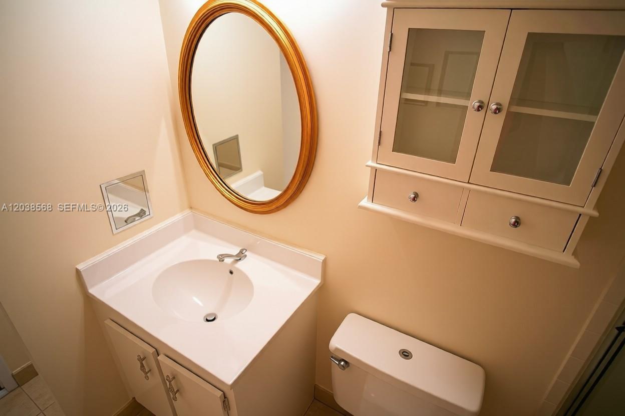 A bathroom features a white vanity, an oval mirror, and a wall-mounted cabinet — 2828 Atlantic Ave # 0, Daytona FL 32118, DAYTONA, FL