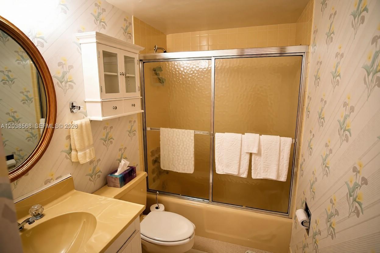A bathroom features floral wallpaper, a beige vanity, a toilet, and a shower-tub combination — 2828 Atlantic Ave # 0, Daytona FL 32118, DAYTONA, FL