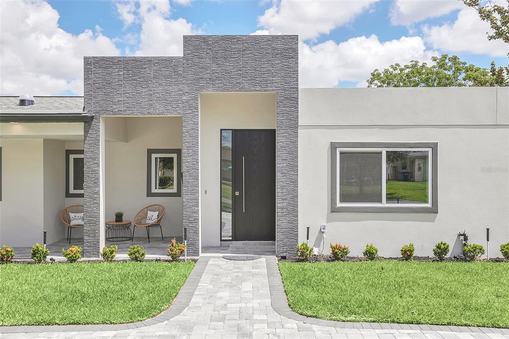 A modern single-story house features a stone-accented entryway, a dark front door, and a paved walkway — 2015 SUMMERFIELD ROAD, WINTER PARK, FL