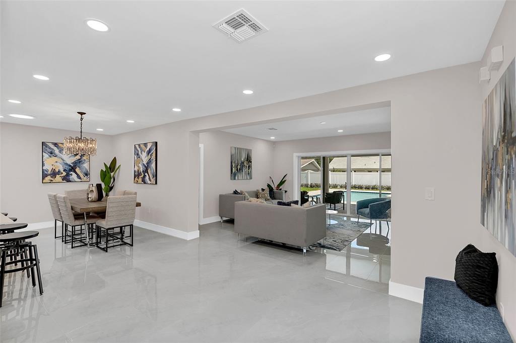 An open-concept living and dining area features light-colored tile flooring and a view of a pool — 2015 SUMMERFIELD ROAD, WINTER PARK, FL