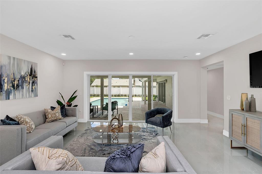 A living room with gray sofas, a glass coffee table, and sliding doors to a pool — 2015 SUMMERFIELD ROAD, WINTER PARK, FL