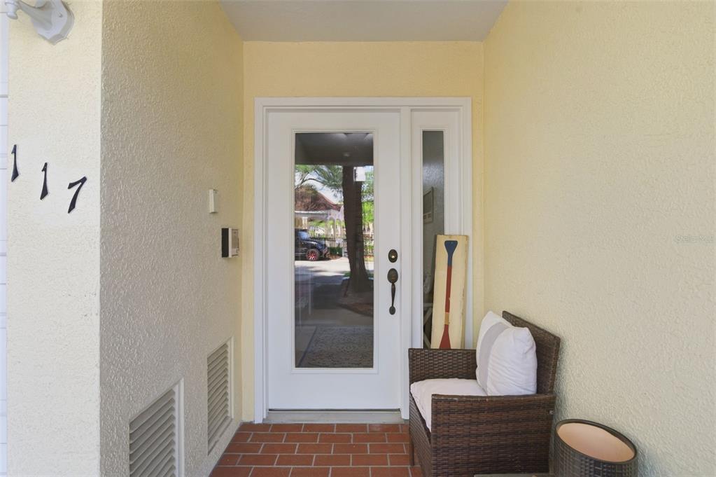 A front entryway features a white door with a glass panel, brick flooring, and seating — 117 BRENT CIRCLE, OLDSMAR, FL