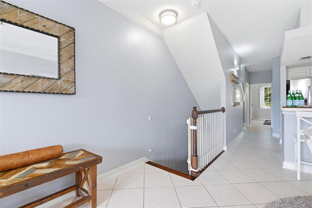A hallway with light gray walls, tile flooring, a wooden bench, and a staircase — 117 BRENT CIRCLE, OLDSMAR, FL