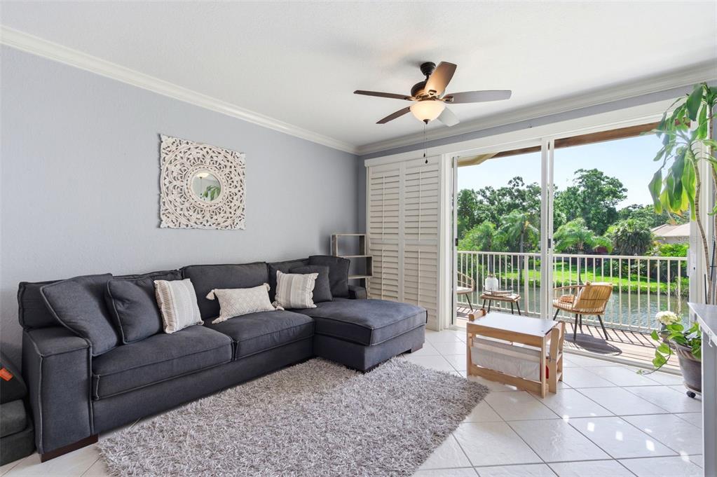 A living room features a gray sectional sofa, a shag rug, and a sliding glass door — 117 BRENT CIRCLE, OLDSMAR, FL