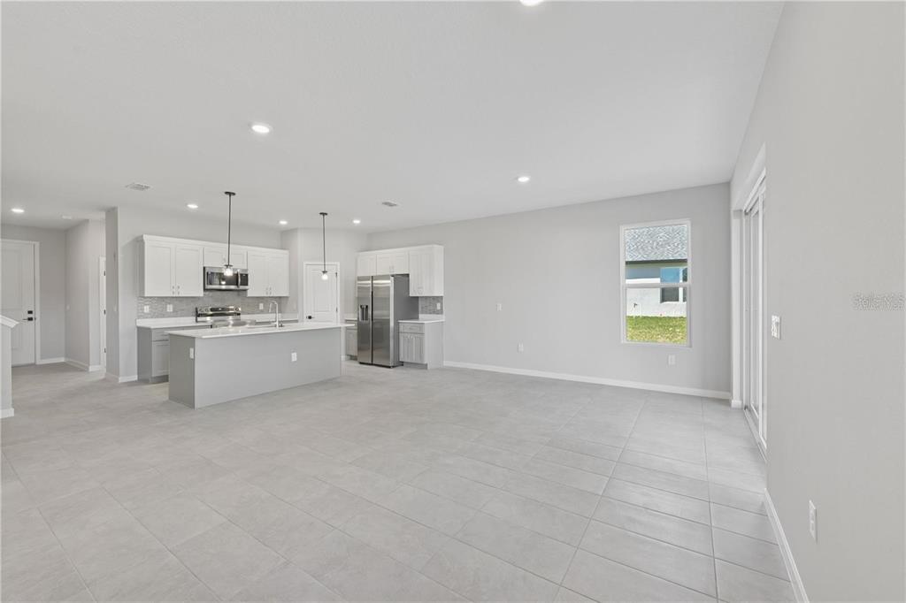 An open-concept kitchen and living area features light gray tile flooring and white cabinetry — 84 SPRINGWOOD DRIVE, PALM COAST, FL