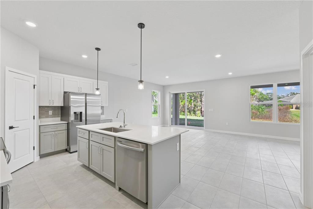 A modern kitchen with a center island, stainless steel appliances, and light gray cabinetry — 84 SPRINGWOOD DRIVE, PALM COAST, FL