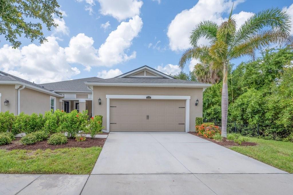 A single-story house with a beige stucco exterior, a two-car garage, and a palm tree — 11505 CAMBIUM CROWN DRIVE, RIVERVIEW, FL