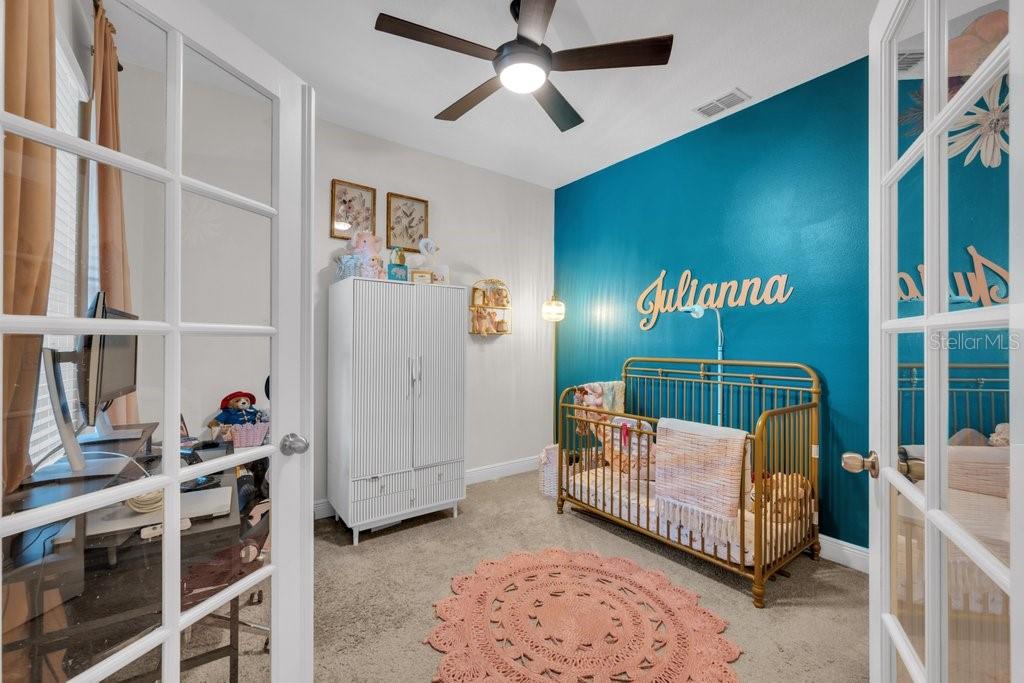 A nursery features a gold crib, a white wardrobe, and a teal accent wall — 11505 CAMBIUM CROWN DRIVE, RIVERVIEW, FL