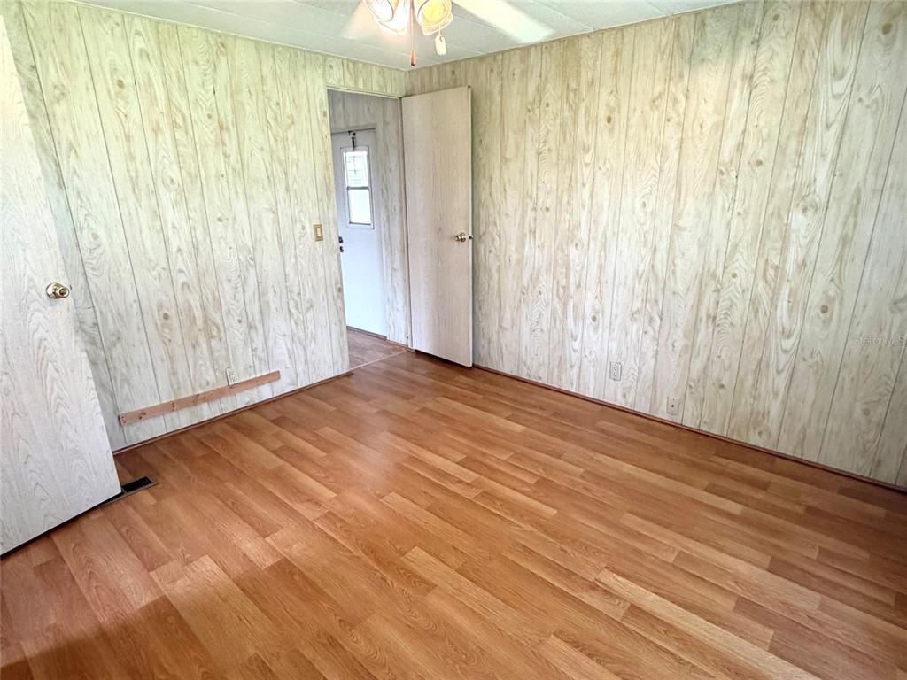 An interior room features wood-paneled walls, wood-look flooring, a ceiling fan, and two doorways — 5562 LANSING DRIVE, WILDWOOD, FL