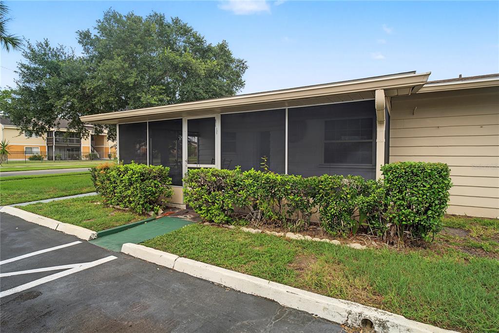 A screened-in porch with a green ramp entrance sits beside a parking lot — 1001 PLANTATION DRIVE UNIT C1, KISSIMMEE, FL
