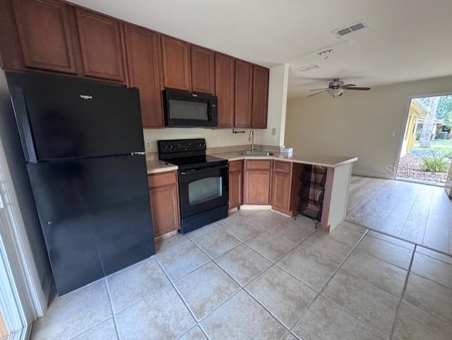 A kitchen features wood cabinets, a black refrigerator, a black stove, and tile flooring — 3152 S BUMBY AVENUE UNIT C3, ORLANDO, FL