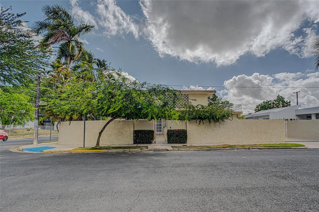 A beige stucco house with a walled courtyard and a tree stands on a corner — 901 HARVARD, SAN JUAN, PR