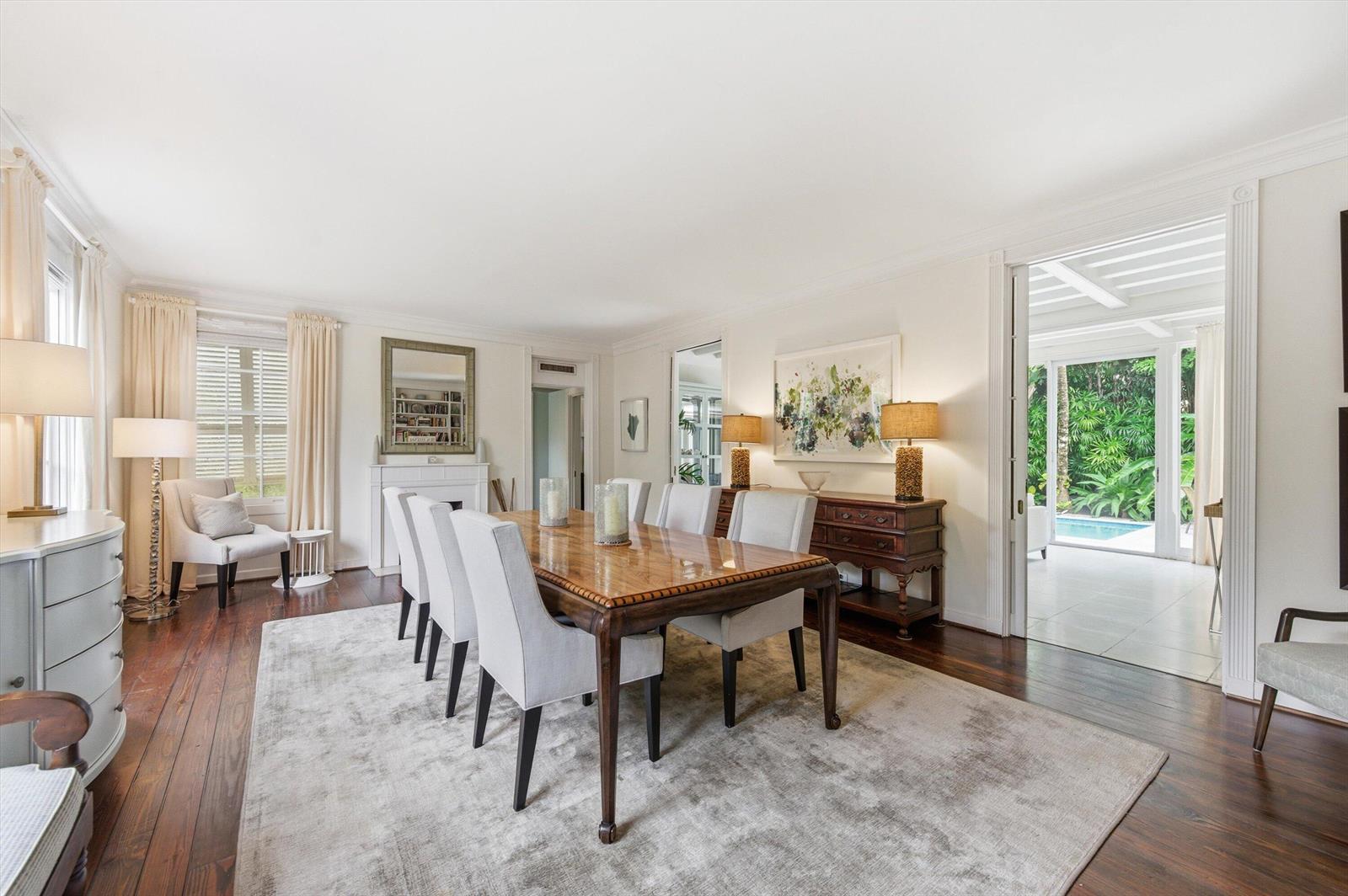 A dining room features a long wooden table, light-colored chairs, and a view of a pool — 258 Pendleton Avenue, Palm Beach FL 33480, PALM BEACH, FL