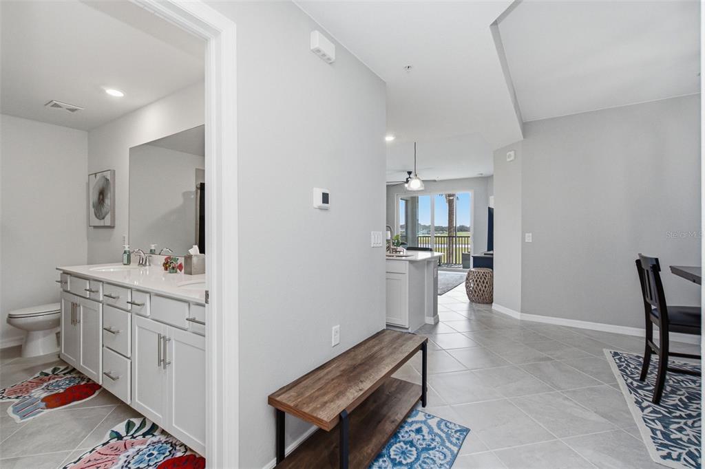 A view from a hallway into a bathroom, dining area, and kitchen with outdoor access — 15275 GREEN ACRES AVENUE UNIT 321, PUNTA GORDA, FL