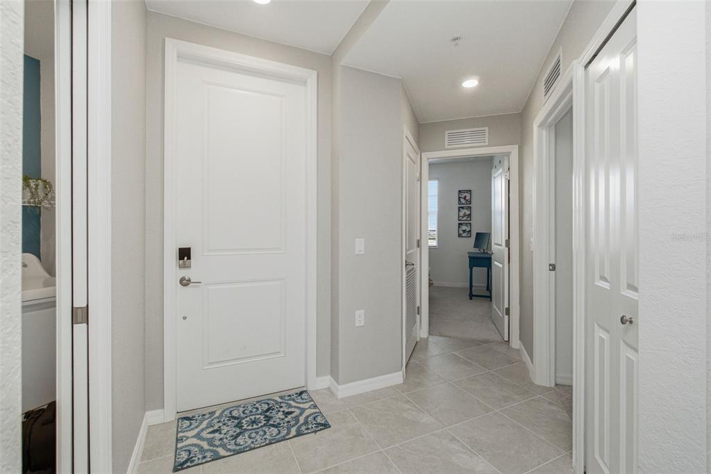 A tiled entryway features a white front door, a patterned rug, and interior doorways — 15275 GREEN ACRES AVENUE UNIT 321, PUNTA GORDA, FL