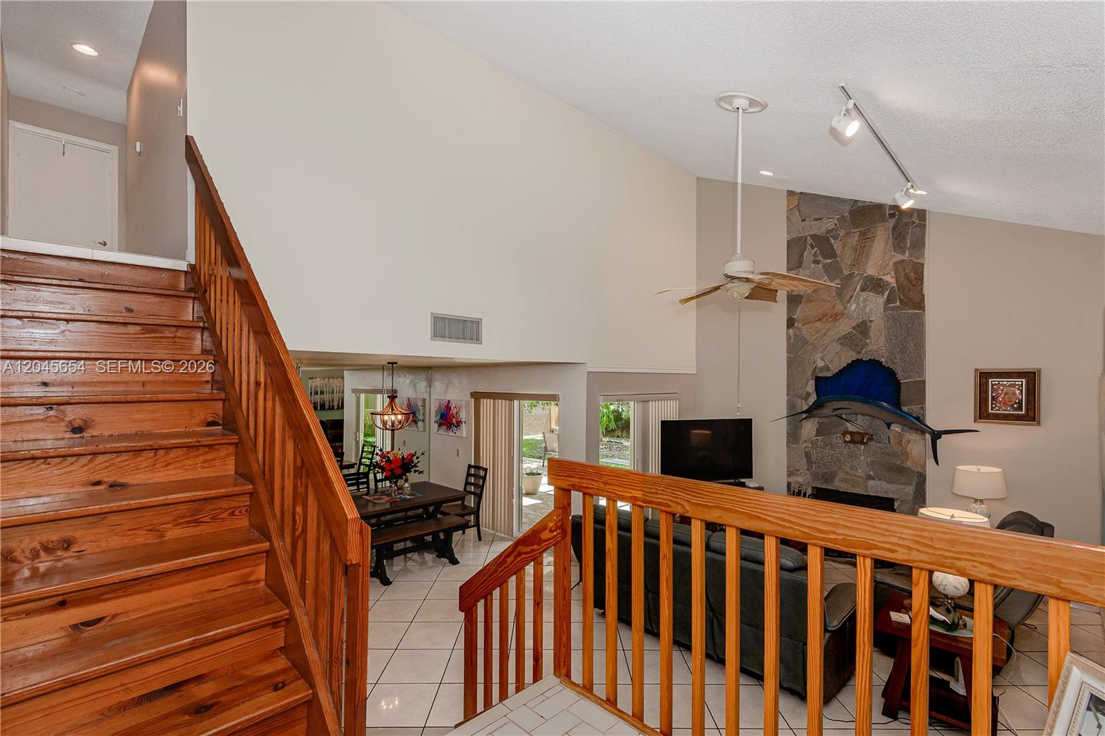 A split-level living area features a wooden staircase, stone fireplace, and tile flooring — 17617 NW 61st Ct N, Hialeah FL 33015, HIALEAH, FL