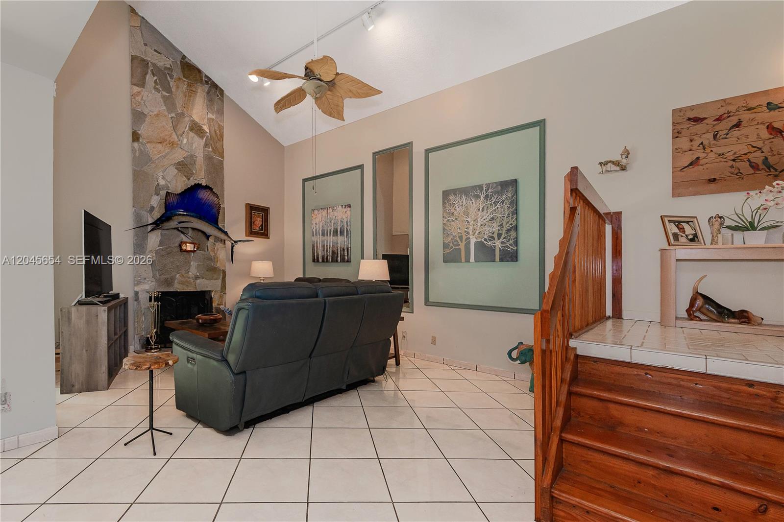 A living room features a stone fireplace, a dark sofa, and a wooden staircase — 17617 NW 61st Ct N, Hialeah FL 33015, HIALEAH, FL