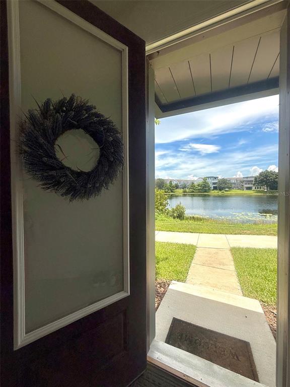 An open front door reveals a view of a lake and a sidewalk outside — 8618 WARBURG ALLEY, ORLANDO, FL