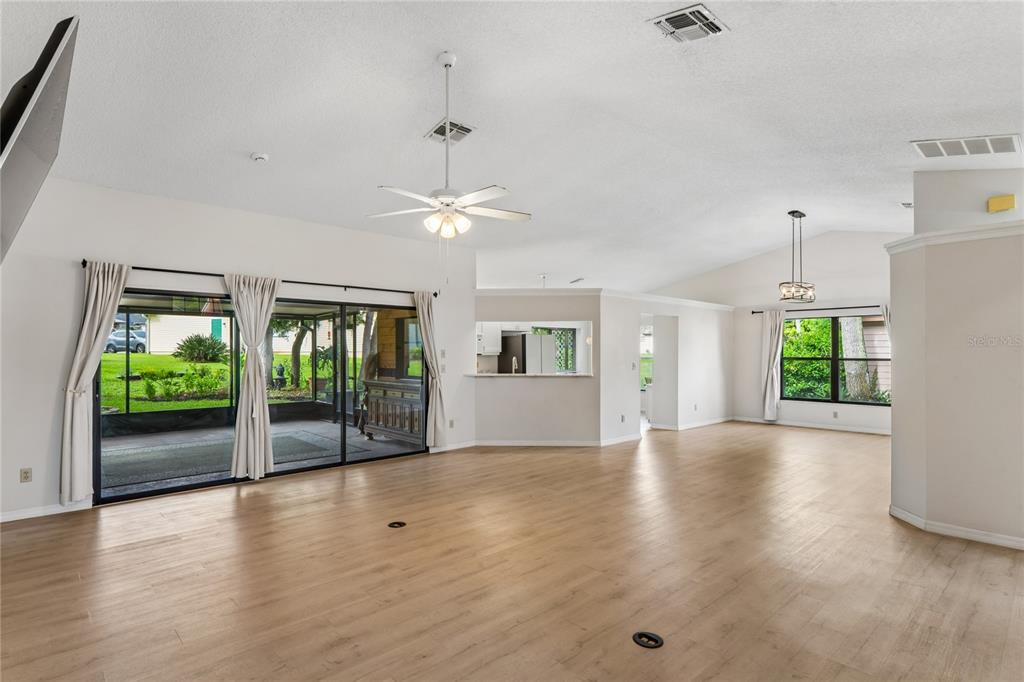 A spacious living area features light wood-look flooring, a ceiling fan, and sliding glass doors — 8050 EACON COURT, HUDSON, FL