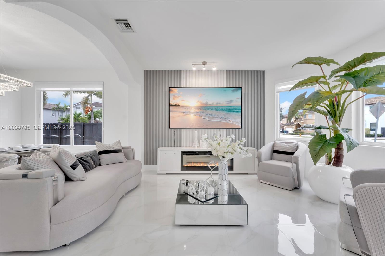 A modern living room features a wall-mounted television, a fireplace console, and white tile flooring — 14452 SW 10th St, Miami FL 33184, MIAMI, FL