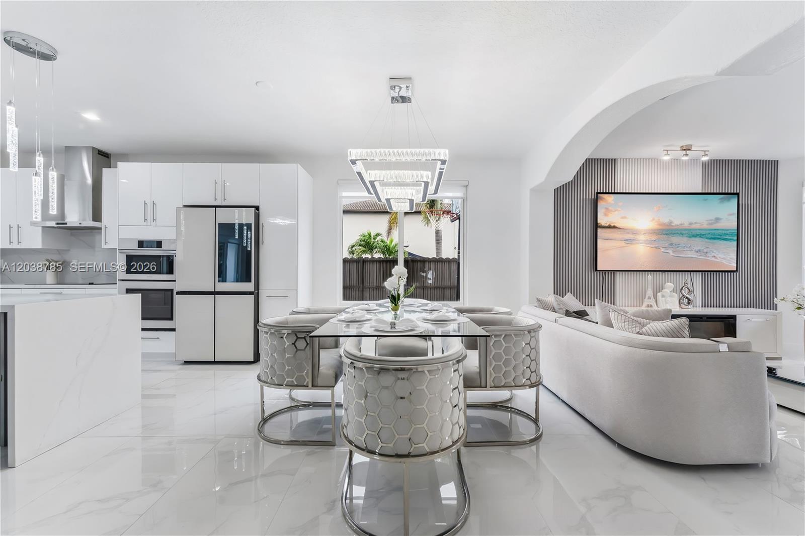 A modern open-concept kitchen and dining area features white cabinetry, marble floors, and a chandelier — 14452 SW 10th St, Miami FL 33184, MIAMI, FL
